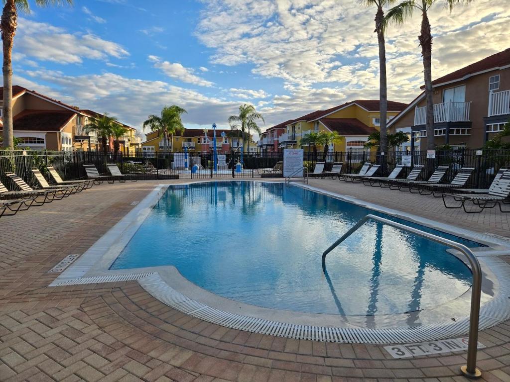 キシミーにあるKissimmee Vacation Beautiful Homeのヤシの木と椅子が備わる大型スイミングプール