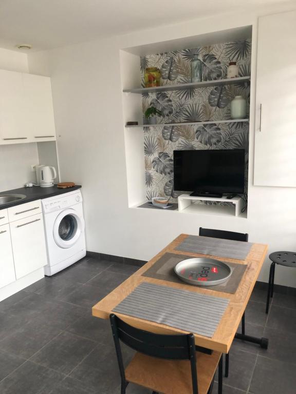 une cuisine avec une table, une cuisinière et un lave-linge dans l'établissement Appartement en RDC avec 1 chambre séparée, à La Celle-sous-Gouzon