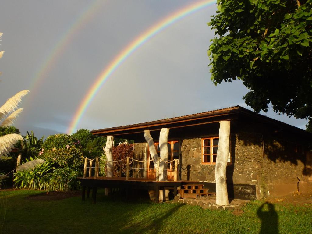 a rainbow in the sky over a house at Cabaña Oreko in Hanga Roa