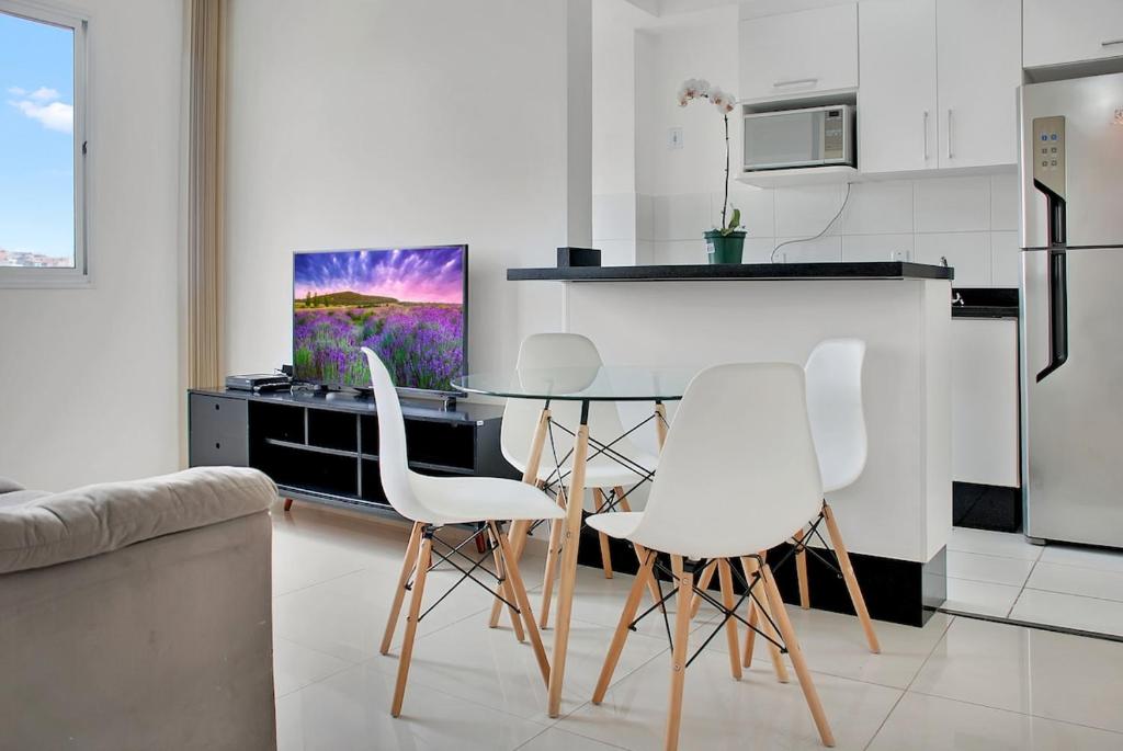 a kitchen with a table and white chairs in a kitchen at 2 Bedrooms Cozy Parking in Carapicuíba