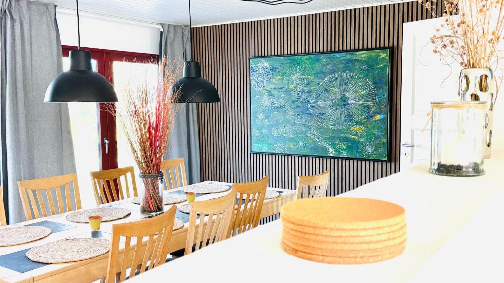 ein Esszimmer mit Tisch und Stühlen und einem Gemälde in der Unterkunft Guest Home Oksbøl in Oksbøl