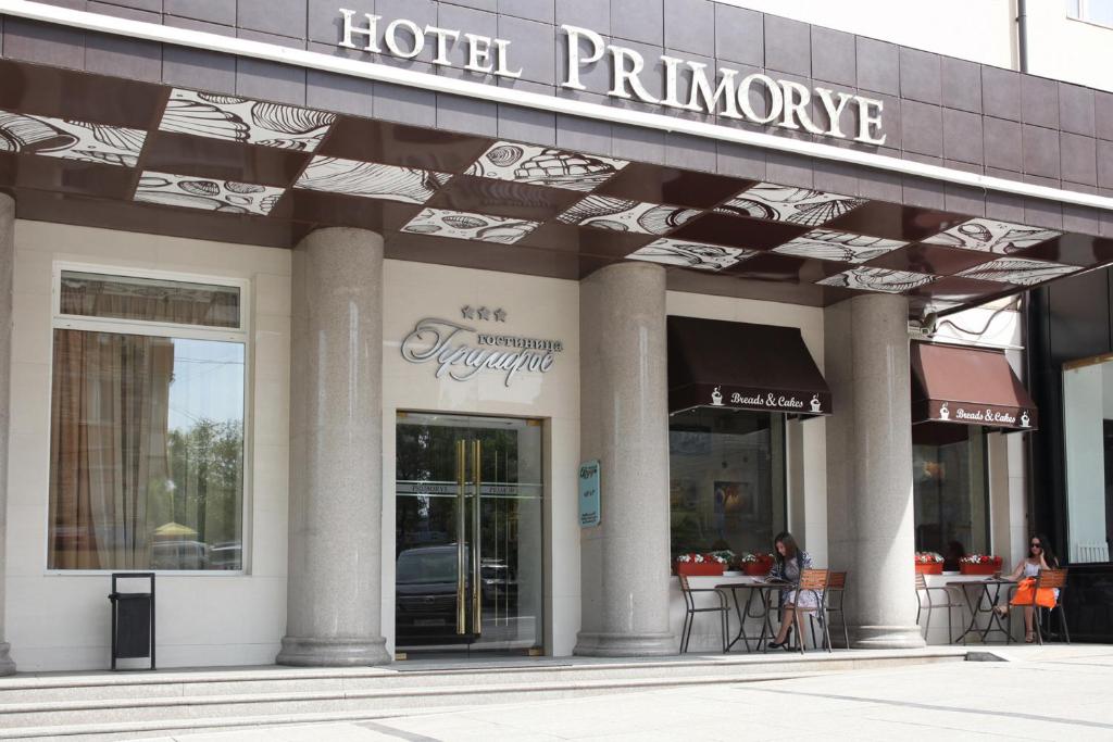 ウラジオストクにあるプリモリエ ホテルの建物の外にテーブルと椅子があるホテルの入り口