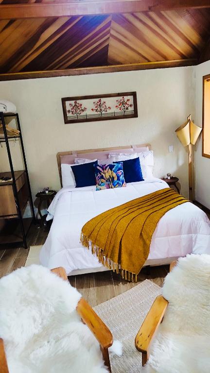a bedroom with two beds with white sheets and blue pillows at Chalé Bosque das Pedras in Núcleo Mauá