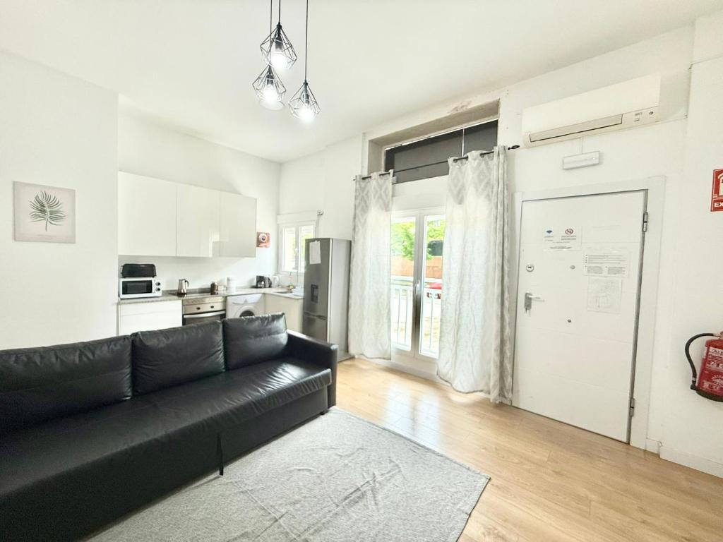 salon z czarną kanapą i kuchnią w obiekcie Aluche Aparment B w Madrycie
