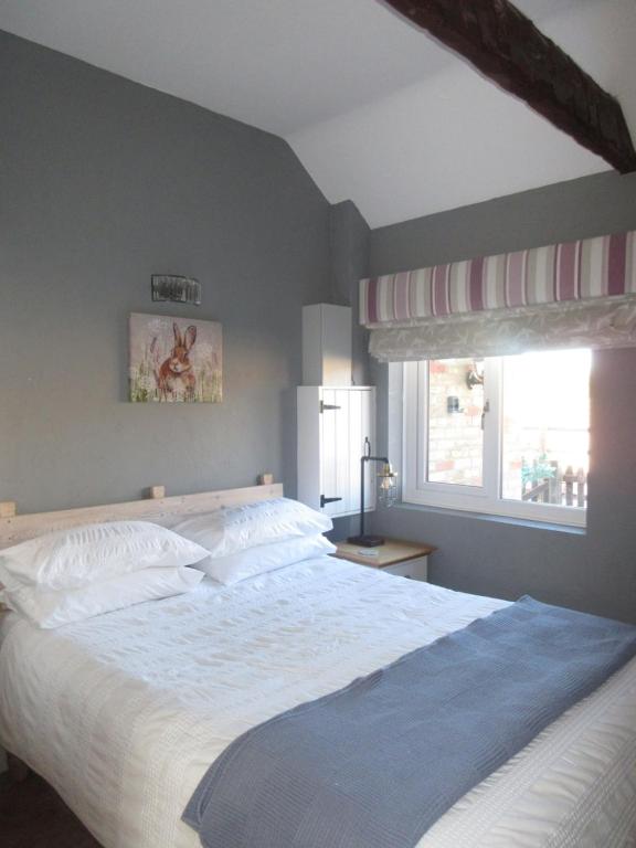 a bedroom with a large white bed and a window at Oxley Cottage in Alford