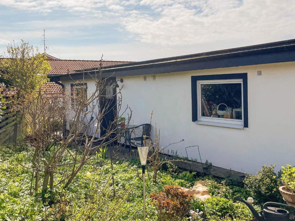 a white house with a window in a yard at 2 person holiday home in BORRBY in Borrby