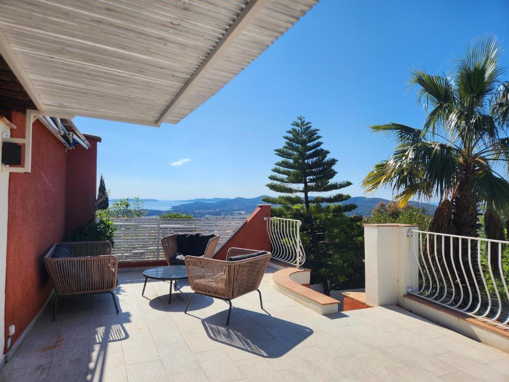 une terrasse avec des chaises, une table et un palmier dans l'établissement Maison village de Bormes-les-Mimosas, à Bormes-les-Mimosas