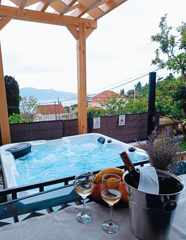 a hot tub with a bottle of wine and wine glasses at Apartment Summer Chill 1 in Trsteno