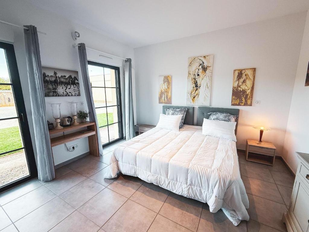 a bedroom with a large bed in a room with windows at Studio cosy dans une ecurie en Touraine in Saint-Roch