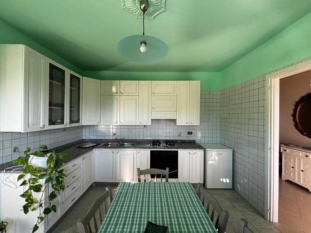 a kitchen with white cabinets and a table with a green ceiling at Rubattiera casa vacanze in Roccasparvera