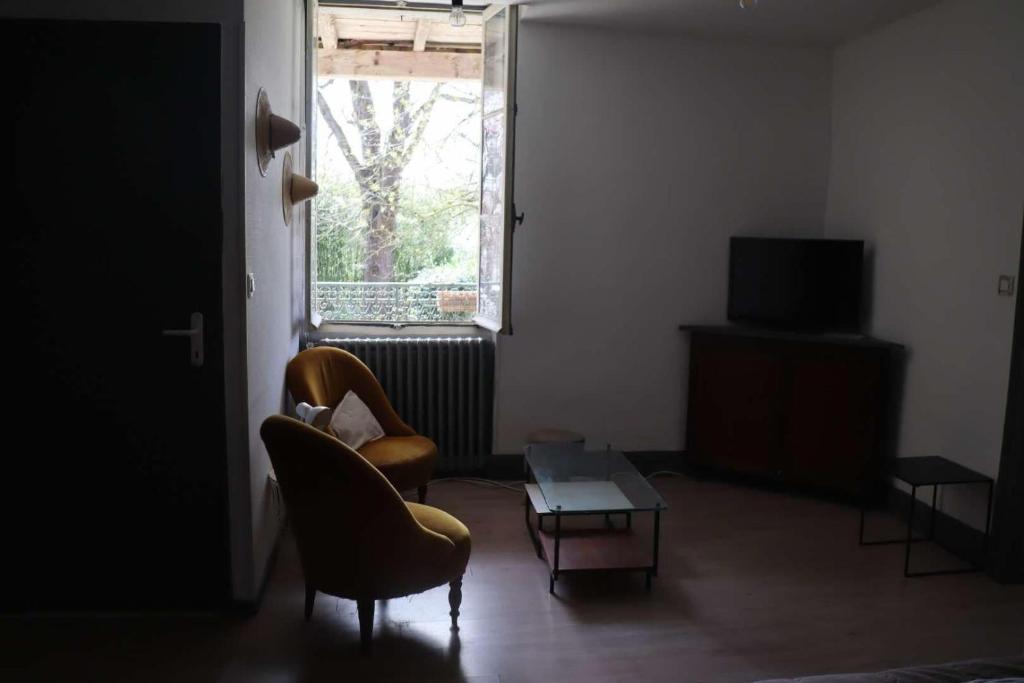 a living room with two chairs and a table and a window at agréables studios avec terrasse sur jardin in Caussade