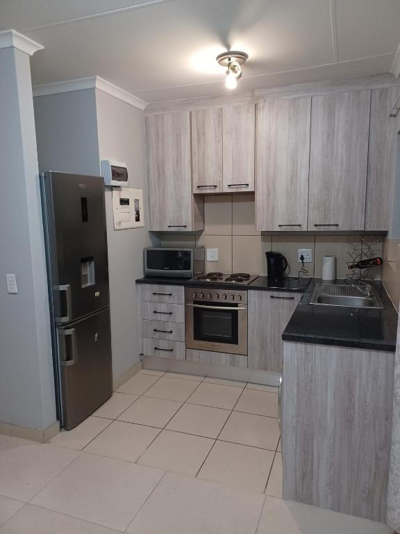 a kitchen with wooden cabinets and a stainless steel refrigerator at Sanctuary at Waterfall in Midrand