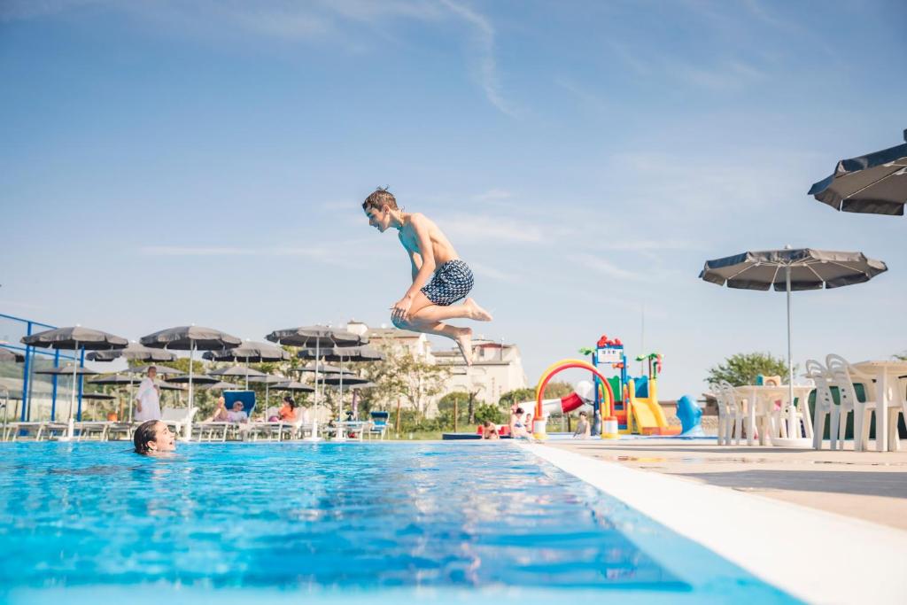 un hombre saltando a una piscina en Hotel Deborah, en Milano Marittima