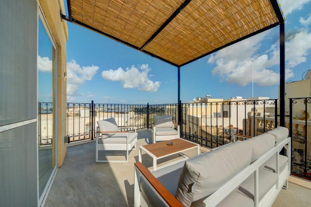 un balcone con mobili bianchi e vista sull'oceano di Ta Karmenu, an 800 year old modernized studio with terrace, by walk to Mdina a Rabat
