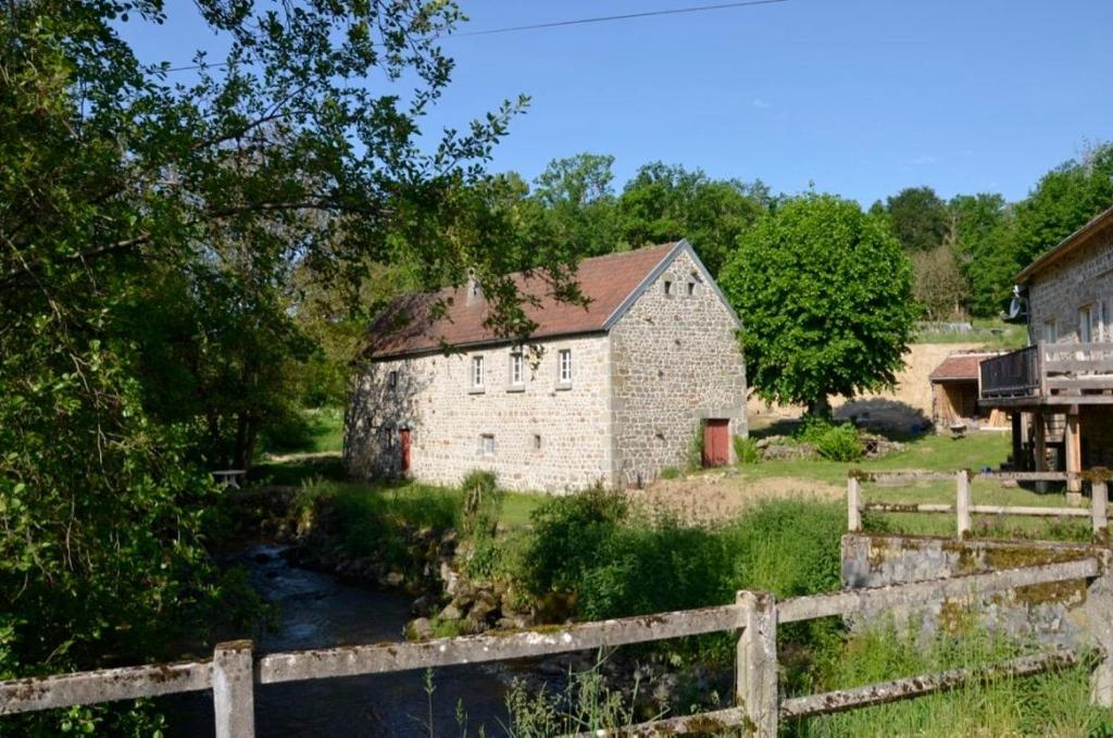 une vieille grange en pierre avec une rivière à côté d'une clôture dans l'établissement Renovated water mill next to the river Tardes, à Saint-Sylvain-Bellegarde
