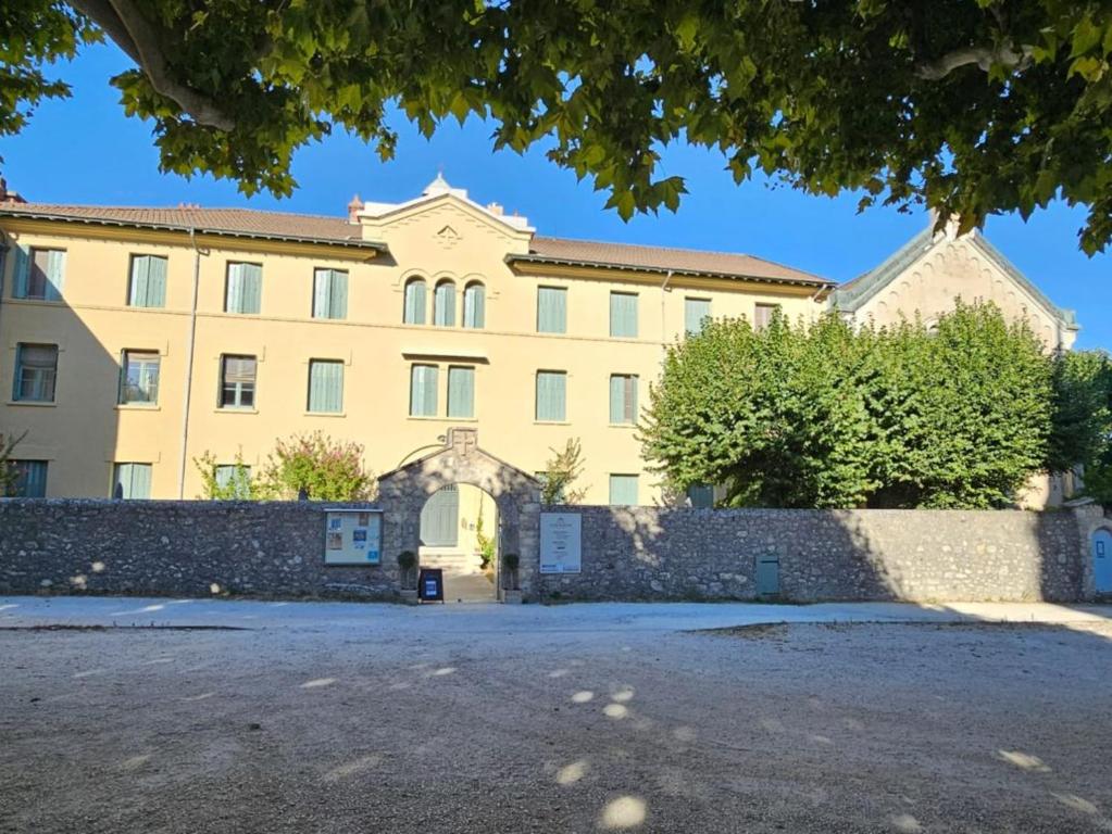 a large yellow building with a fence in front of it at Gîte d'étape et de groupe du Clos Saint Roch in Viviers