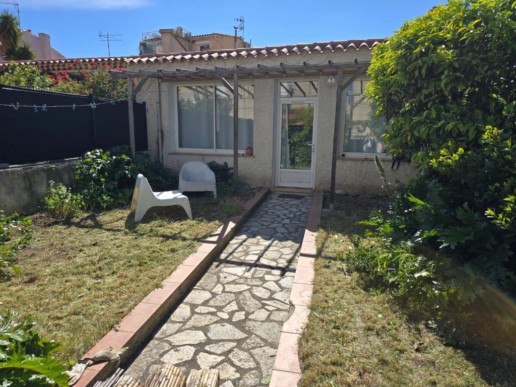 un jardín con una silla blanca y una casa en Maison proche du port de La Ciotat, en La Ciotat