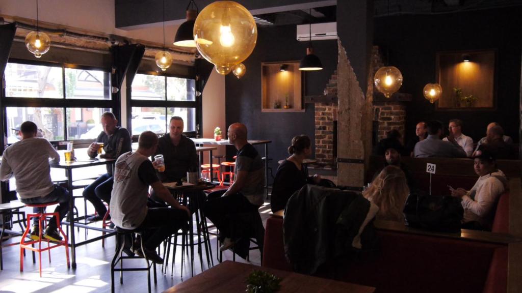 un grupo de personas sentadas en mesas en un restaurante en Pint On Punt Backpackers, en Melbourne