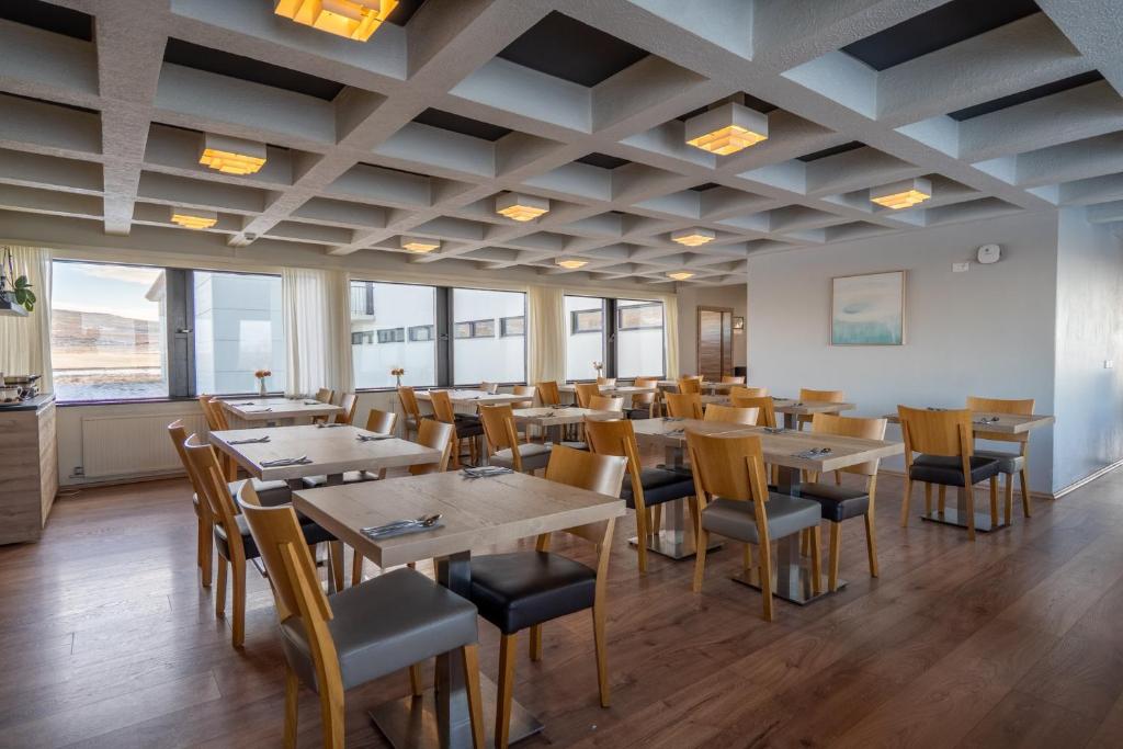a restaurant with wooden tables and chairs and windows at Hótel Laugarbakki in Laugarbakki
