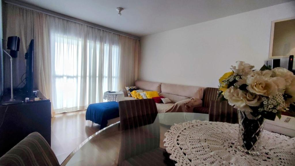 a living room with a glass table with a vase of flowers at Apartamento Vista Parque in Cascavel