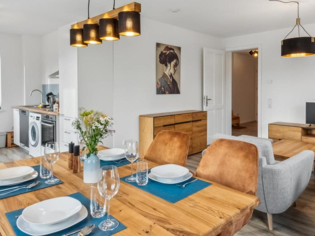 a dining room and living room with a wooden table and chairs at Familienfreundliches Apartment zwischen Potsdam und Berlin für 2-4 Personen - Parkplatz - Balkon - Voll ausgestattete Küche - WLAN - Ferienwohnung Nebelwiesen Stahnsdorf in Stahnsdorf