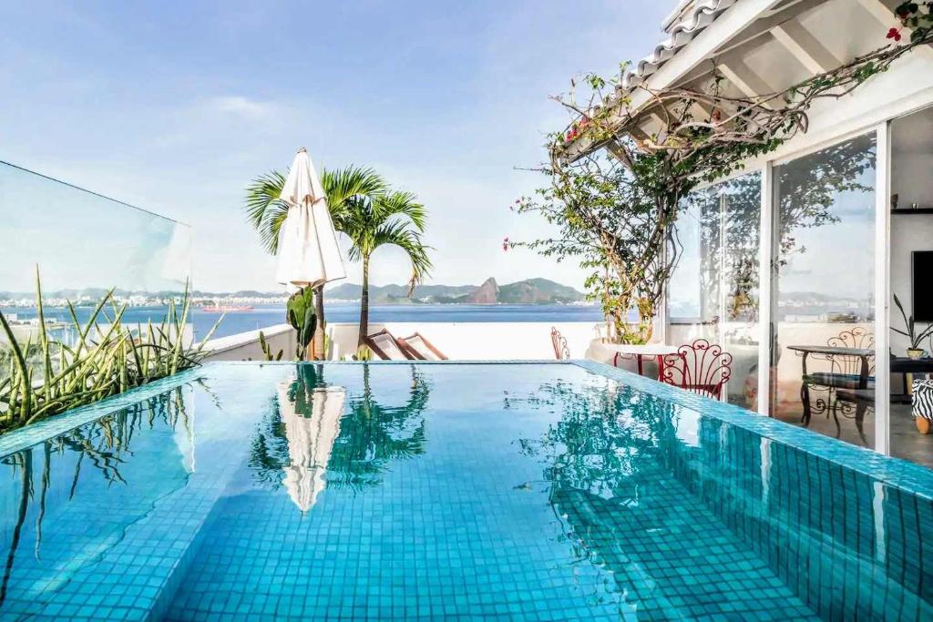a swimming pool with an umbrella and the ocean at Lux 12 - Cobertura Romantica com piscina aquecida e vista mar in Rio de Janeiro