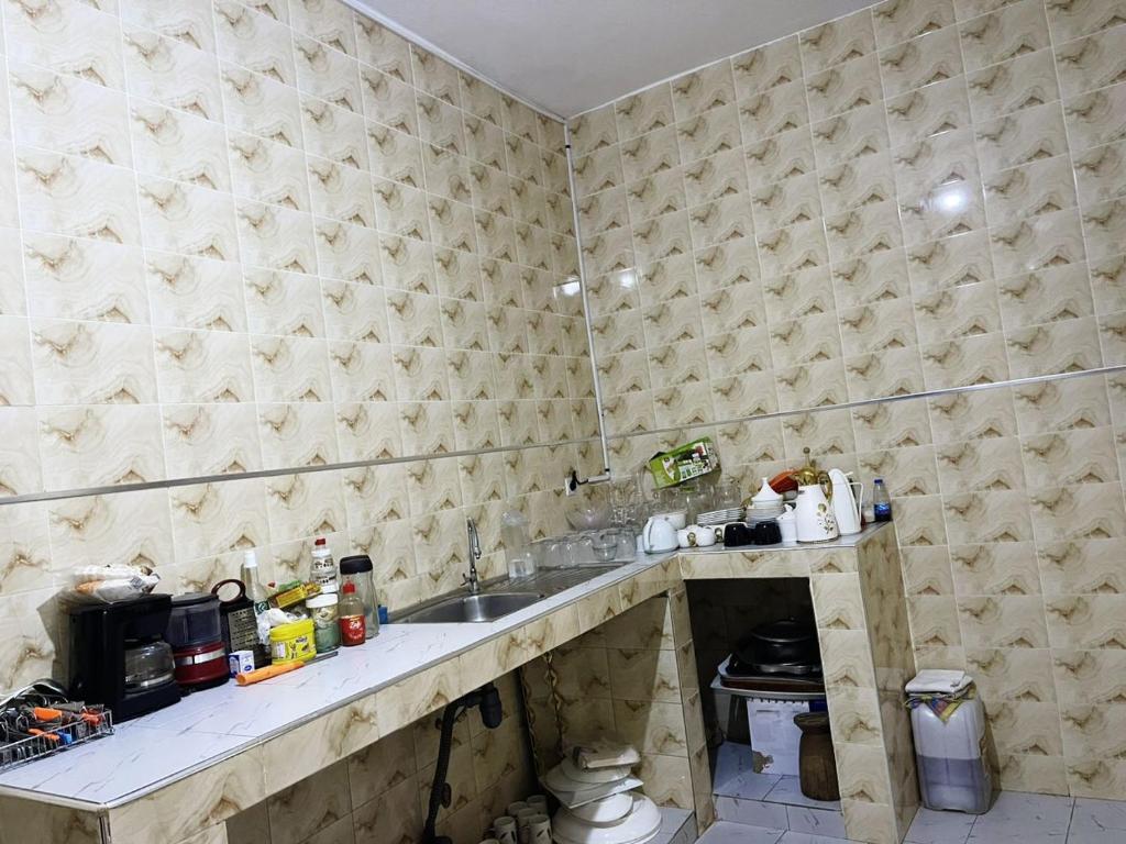 a kitchen with a sink and a tiled wall at Mame Thierno sene in Niakoul Rap