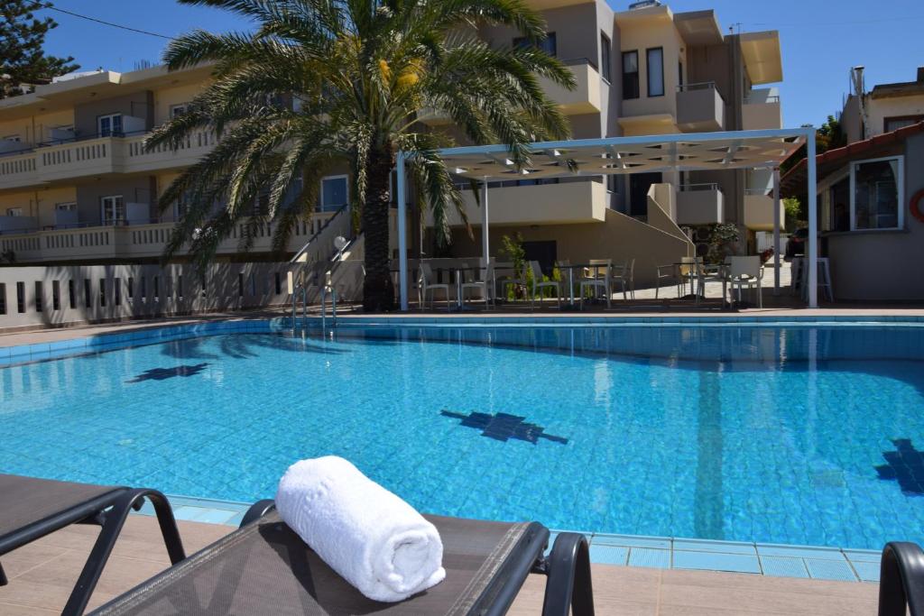 a hotel swimming pool with a towel on a chair at Amaryllis in Platanias