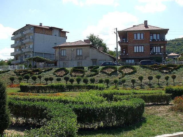 a garden with bushes and a building in the background at ELIT Holiday Village in Obzor