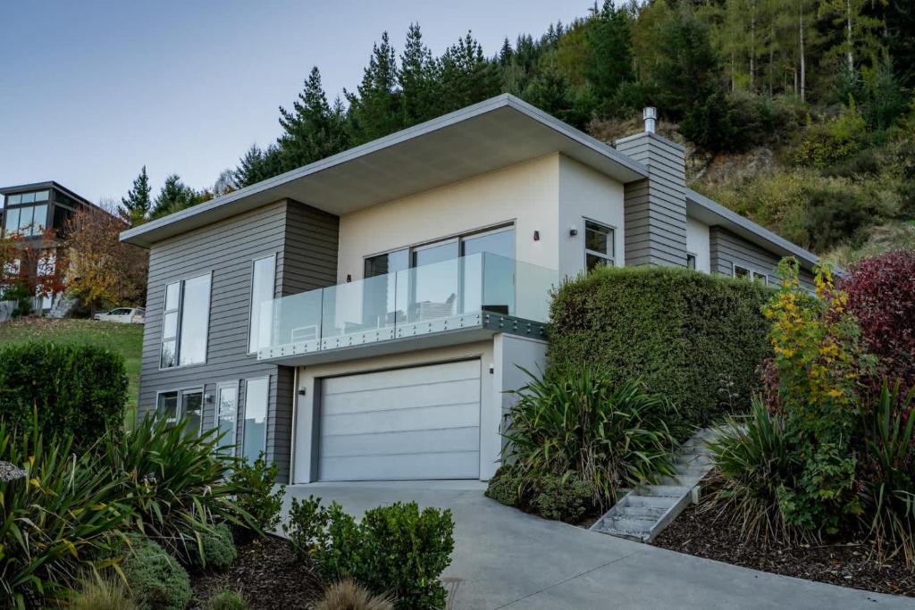 a house with a garage and some bushes at Remarkables View Eco House in Queenstown