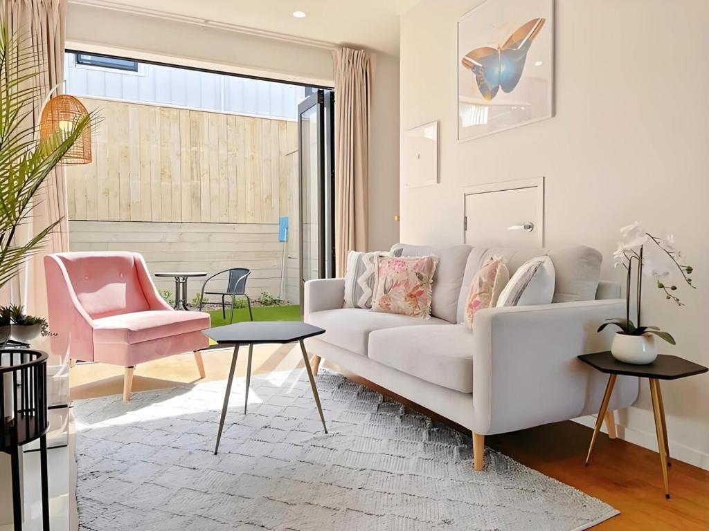 sala de estar con sofá blanco y silla rosa en 2BR City Townhouse with air con Courtyard and Parking, en Auckland