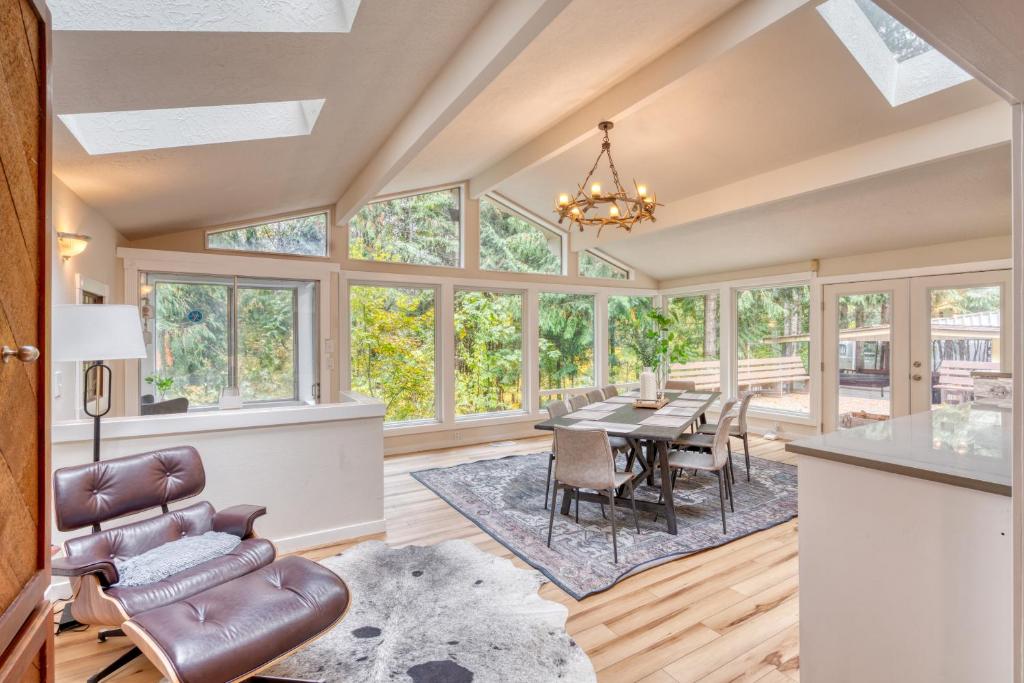a dining room with a table and chairs and windows at Stay Portland - Sandy Riverfront Mt Hood Cabin! 9 Queen Beds! in Rhododendron