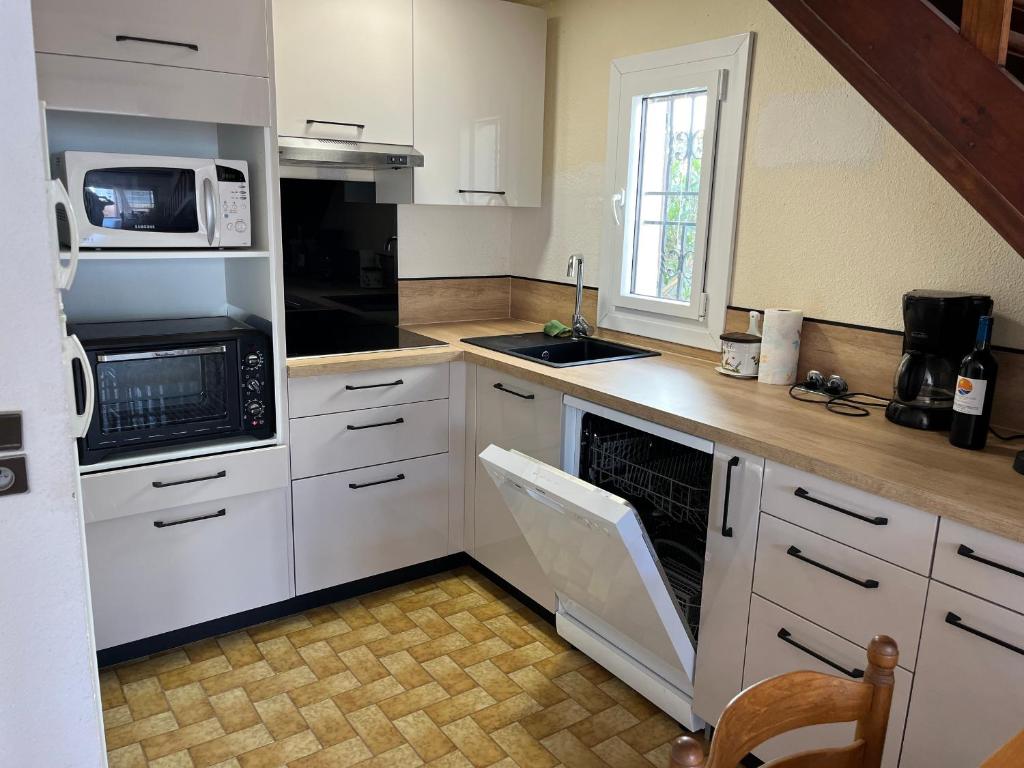 une cuisine avec des armoires blanches et un four à plaques de cuisson dans l'établissement Villa Climatisée 6 Pers - Proche Port & Village - Parking Privé - FR-1-796-88, à Gruissan