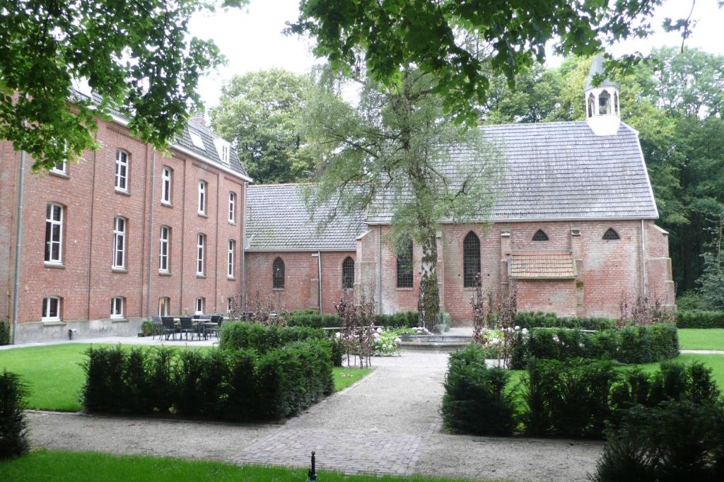um grande edifício de tijolos com um pátio em frente em Klooster Nieuwkerk Goirle em Goirle