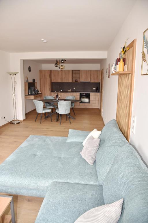 a living room with a blue couch and a kitchen at Ferienwohnung Eder in Bad Birnbach