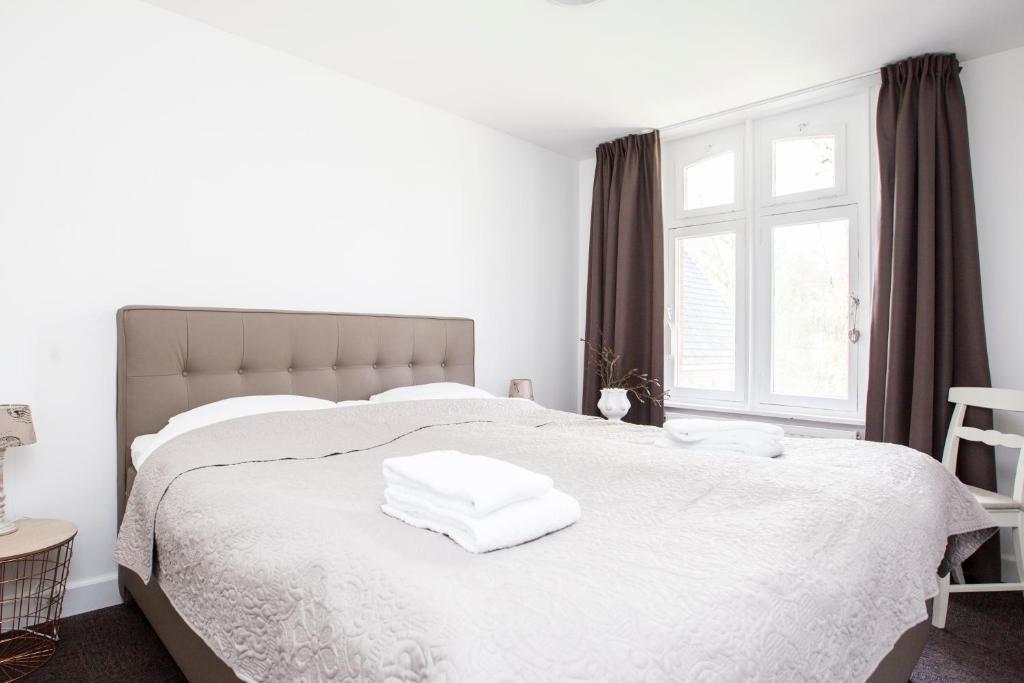 a bedroom with a white bed with towels on it at Klooster Nieuwkerk Goirle in Goirle