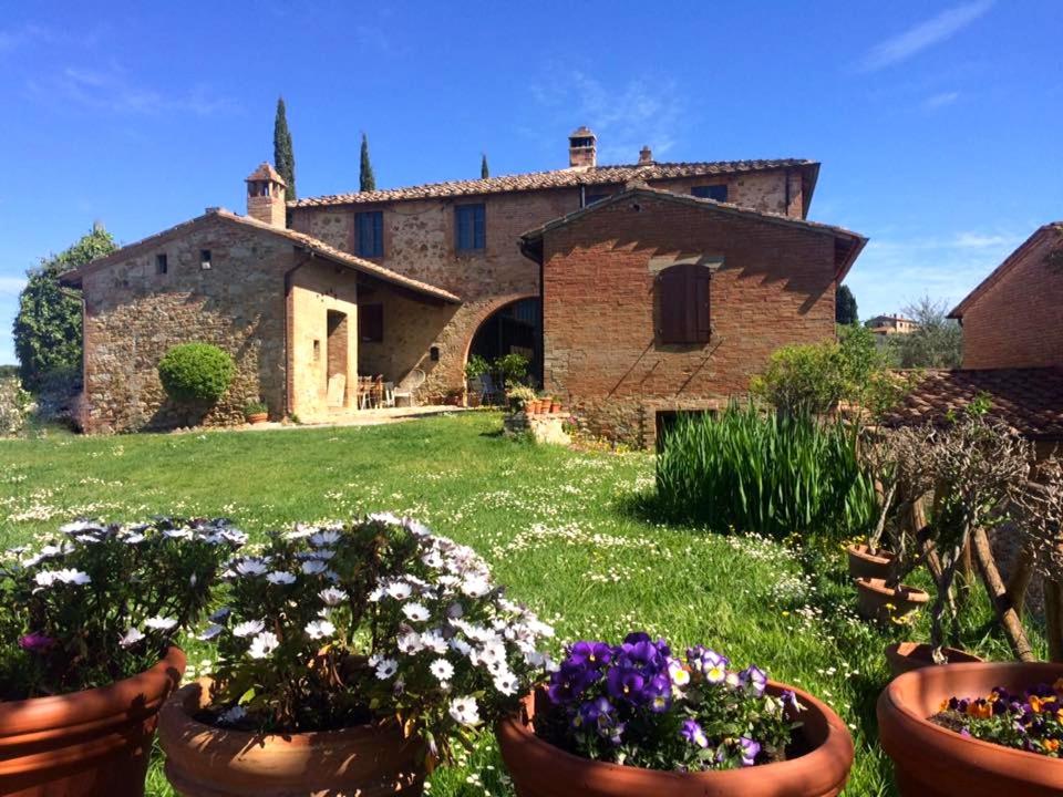 una vieja casa de piedra con flores en un patio en Casa Cernano, en Castelnuovo Berardenga