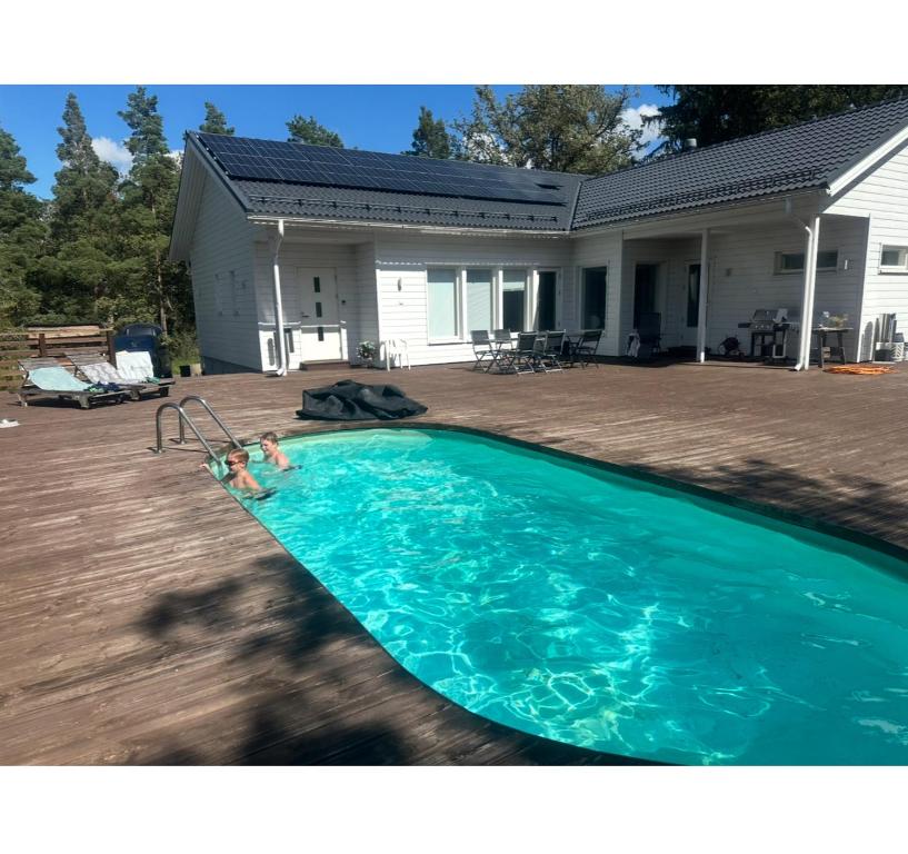 deux personnes dans une piscine devant une maison dans l'établissement Lomamökki 25 km Turusta, à Masku
