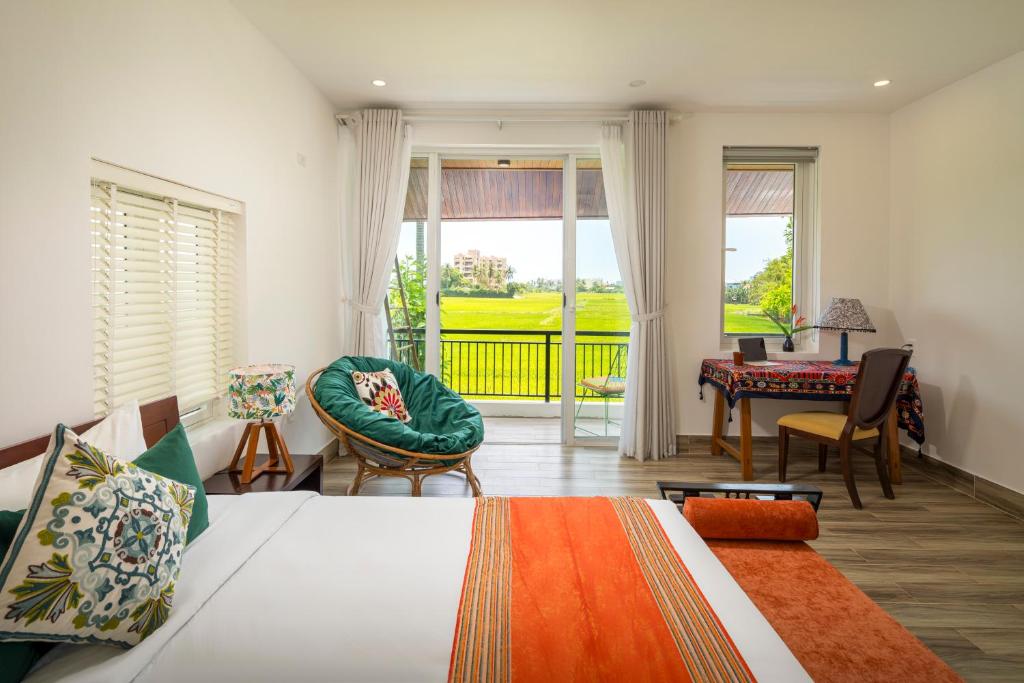Un dormitorio con una cama y un escritorio y un balcón. en Hoi An Private Pool Villa - Peaceful Rice Paddy Views, en Hoi An