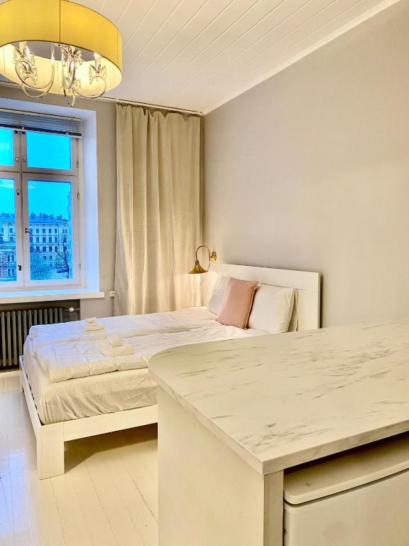 a white bedroom with a bed and a window at Katas Suite, Helsinki city center in Helsinki