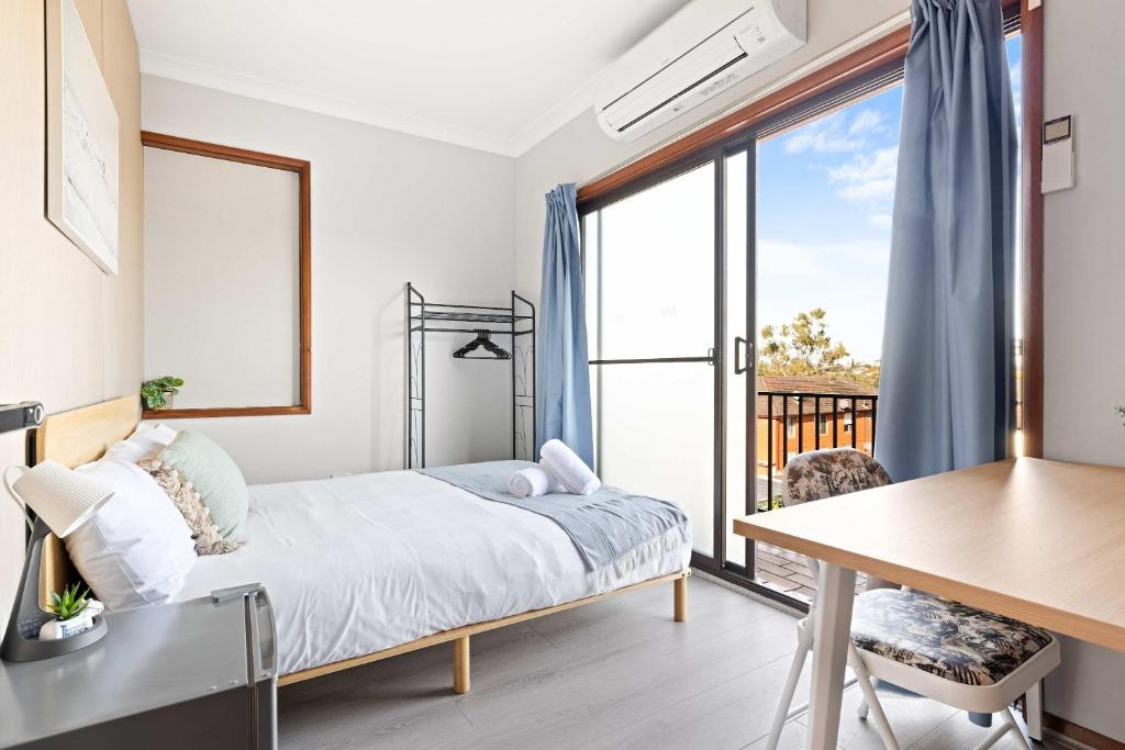 シドニーにあるComfortable Single Room in Convenient Belmore Location - Shared Bathroomのベッドルーム(ベッド1台、デスク、バルコニー付)