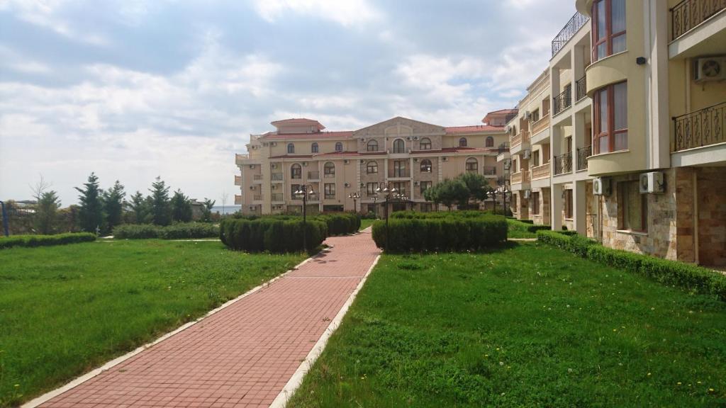 a building with a brick walkway in front of a green field at MAISONETTES in Royal Bay Residence and SPA in Sveti Vlas