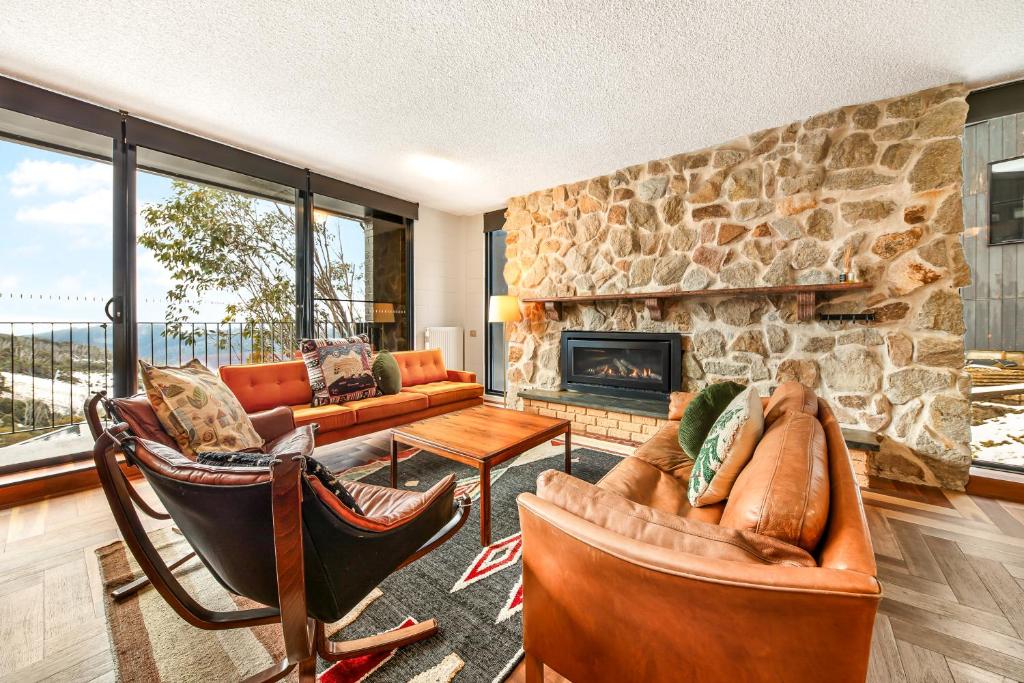 een woonkamer met banken en een stenen open haard bij Pontresina 1 in Falls Creek