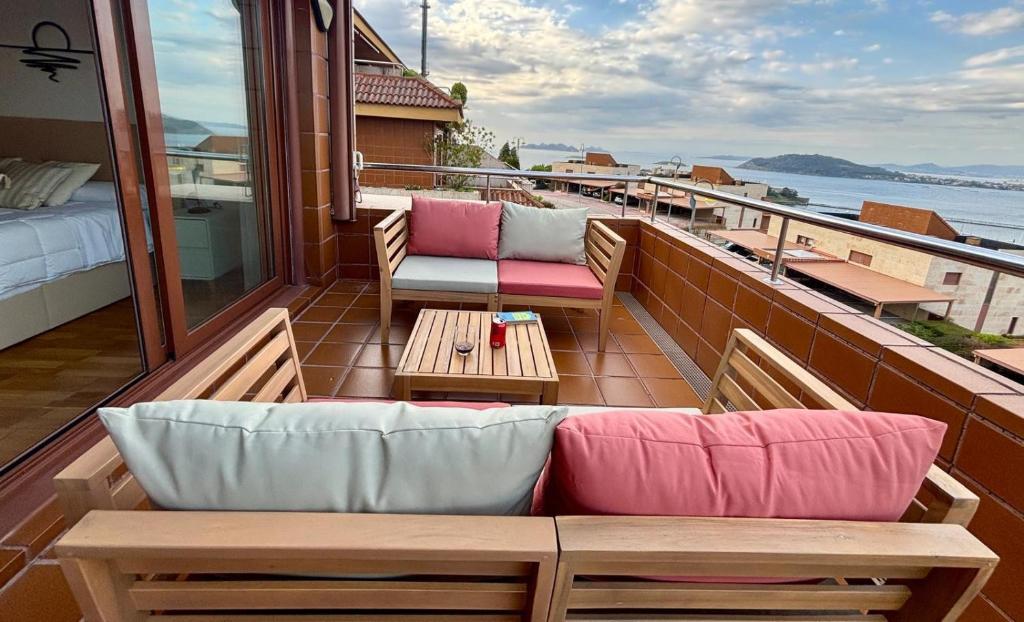 un balcone con un divano, un letto e dei tavoli di Holibai, Son do Mar Son do Mar, Lujo sereno frente al Atlántico, Baiona a Baiona