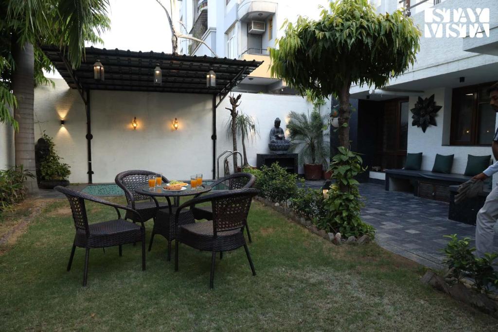 a patio with a table and chairs in a yard at StayVista at House of Palm with Bonfire & Pool in Jaipur