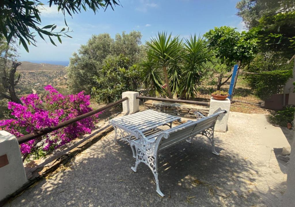 a white bench sitting on a balcony with flowers at Kotseli - Sea View, Pool, Sunsets in Andros