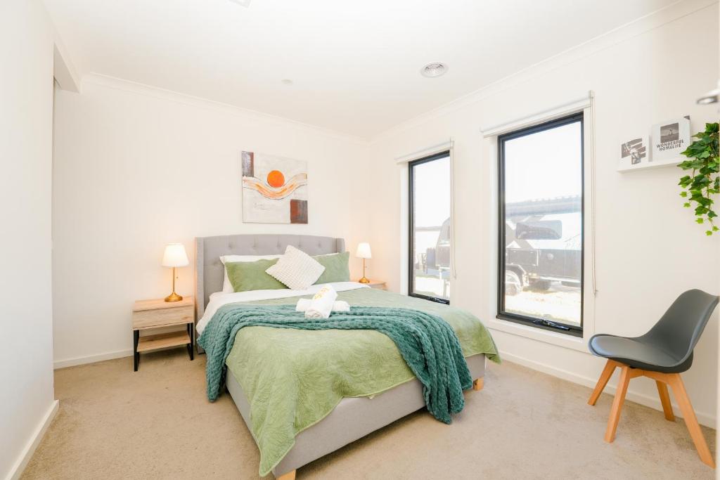 a bedroom with a bed and a chair and windows at New family-friendly home in Melton South