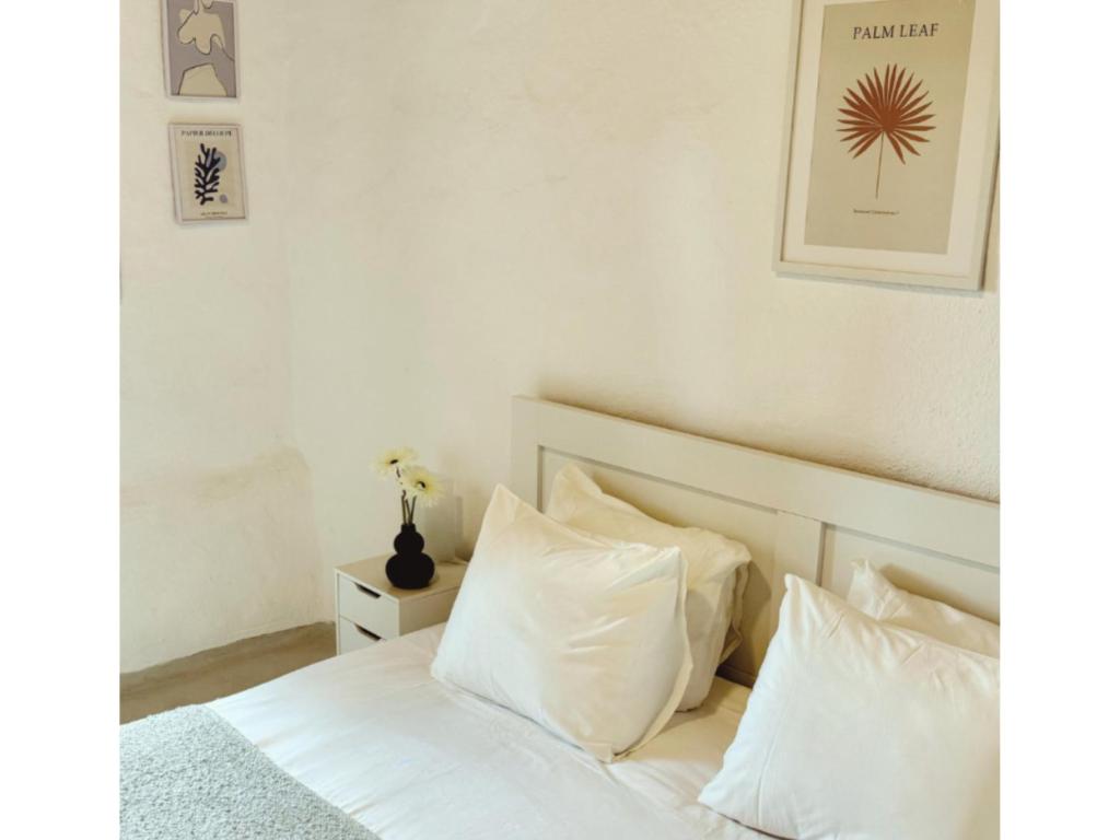 a bedroom with a bed with white sheets and pillows at Kotseli - Sea View, Pool, Sunsets in Andros