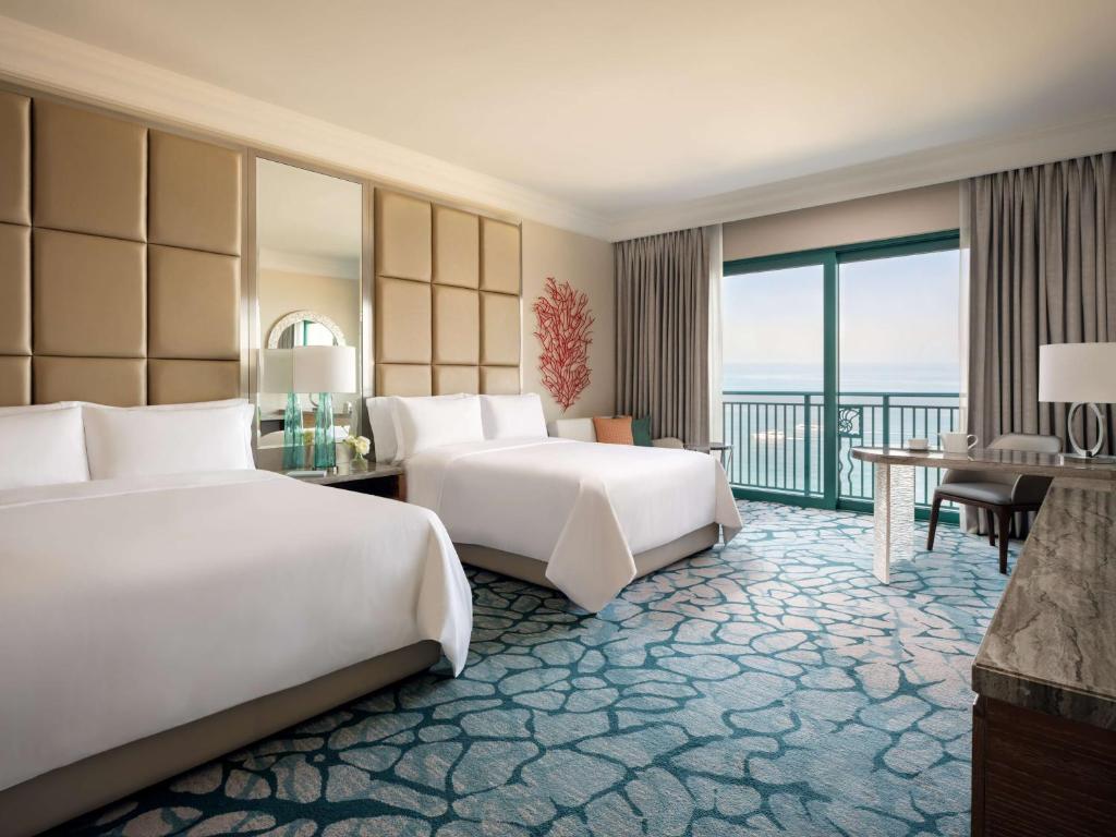 a hotel room with two beds and a balcony at Atlantis, The Palm in Dubai