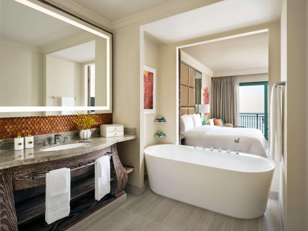 a bathroom with a large mirror and a tub and a bed at Atlantis, The Palm in Dubai
